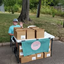 A young volunteer staffing boxes of donated supplies