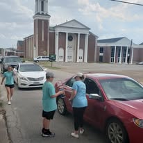 A team serving a line of vehicles outside the church