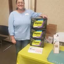 A volunteer beside donated diaper supplies