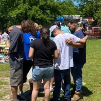 Volunteers gathering closely for prayer during the outreach