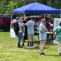 Volunteers welcoming neighbors beneath an outreach tent