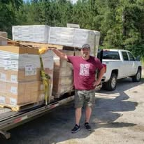 A volunteer beside pallets of donated goods