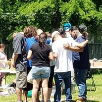 Volunteers and neighbors praying together outdoors