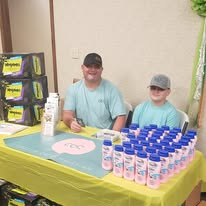Two volunteers behind a table filled with personal-care supplies