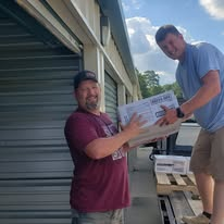 Two volunteers unloading a large donation box