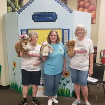 Three volunteers sharing a joyful moment with puppies